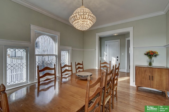 dining space with ornamental molding, an inviting chandelier, and light wood-type flooring