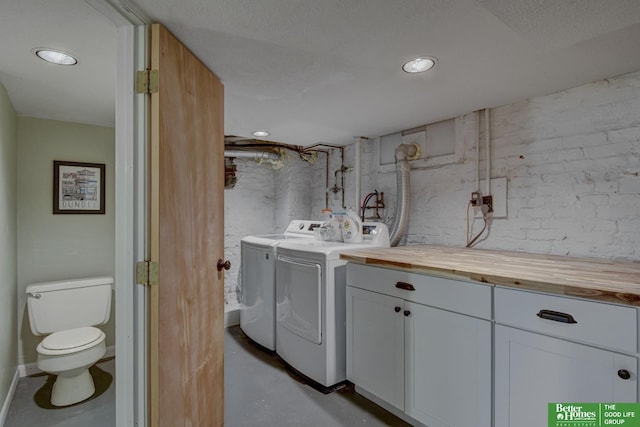 clothes washing area with brick wall and washing machine and dryer