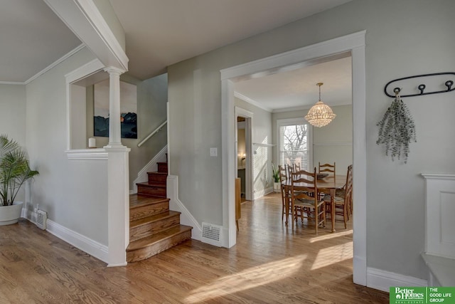 staircase with ornamental molding, hardwood / wood-style floors, and decorative columns