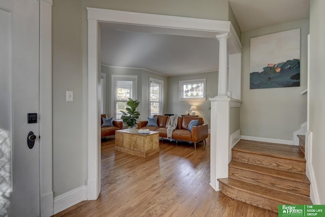 foyer featuring light wood-type flooring and ornate columns