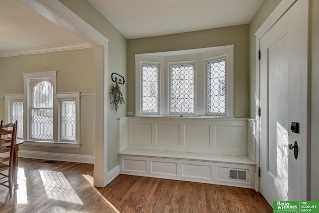 foyer entrance featuring ornamental molding, a wealth of natural light, and light hardwood / wood-style floors