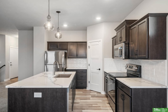 kitchen featuring dark brown cabinetry, hanging light fixtures, light hardwood / wood-style flooring, an island with sink, and stainless steel appliances