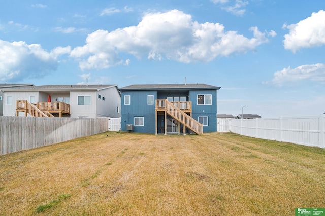 rear view of property featuring cooling unit, a wooden deck, and a lawn