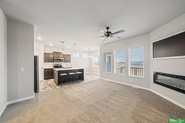 carpeted living room featuring ceiling fan with notable chandelier and sink