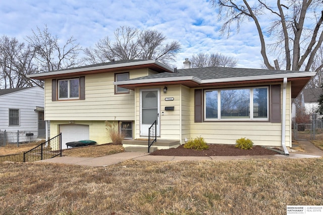 tri-level home featuring a garage and a front lawn