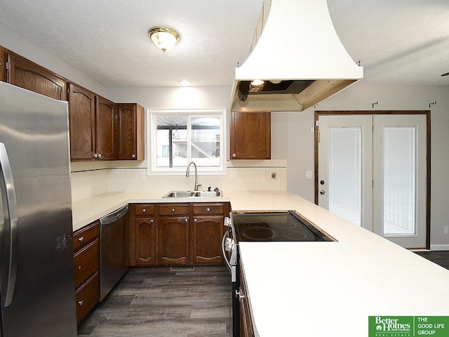 kitchen with sink, island range hood, a textured ceiling, dark hardwood / wood-style flooring, and stainless steel appliances