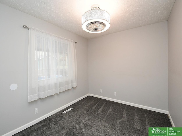 empty room with a textured ceiling and dark colored carpet