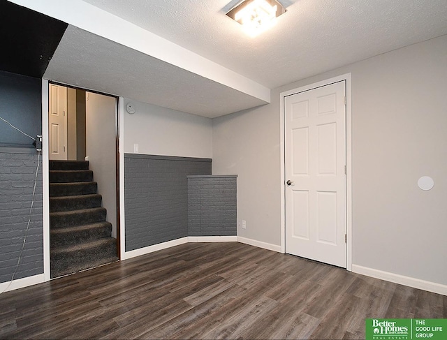 basement featuring dark wood-type flooring and a textured ceiling