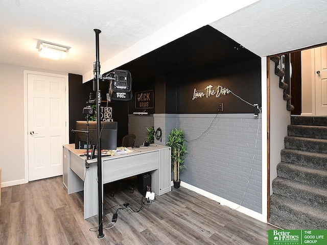 interior space with brick wall, hardwood / wood-style floors, and a textured ceiling