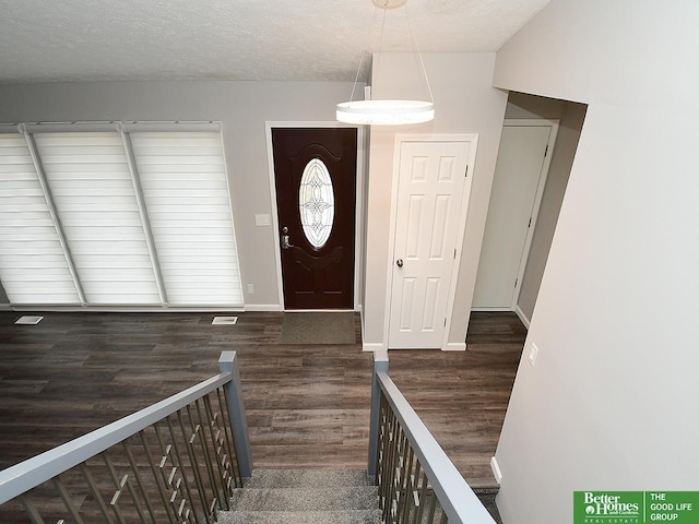 foyer entrance with dark wood-type flooring and a textured ceiling