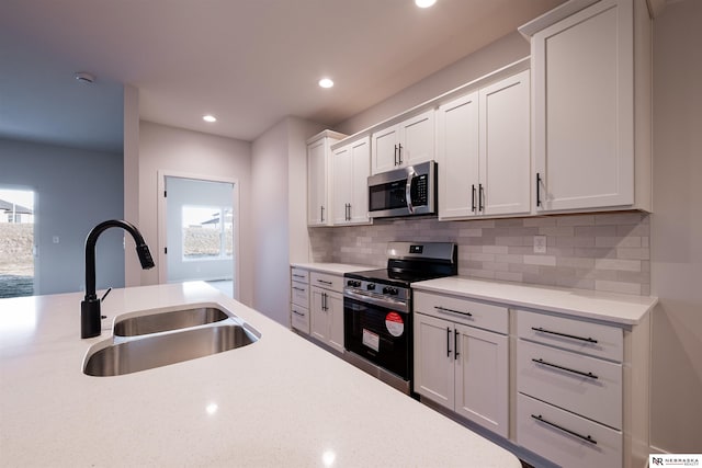 kitchen featuring white cabinetry, sink, backsplash, stainless steel appliances, and plenty of natural light