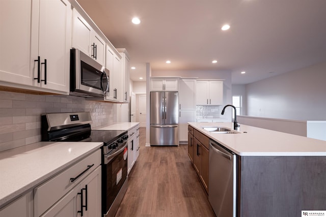 kitchen with a kitchen island with sink, sink, white cabinets, and appliances with stainless steel finishes