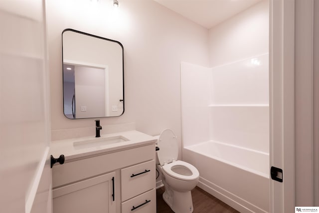 full bathroom with hardwood / wood-style flooring, washtub / shower combination, vanity, and toilet