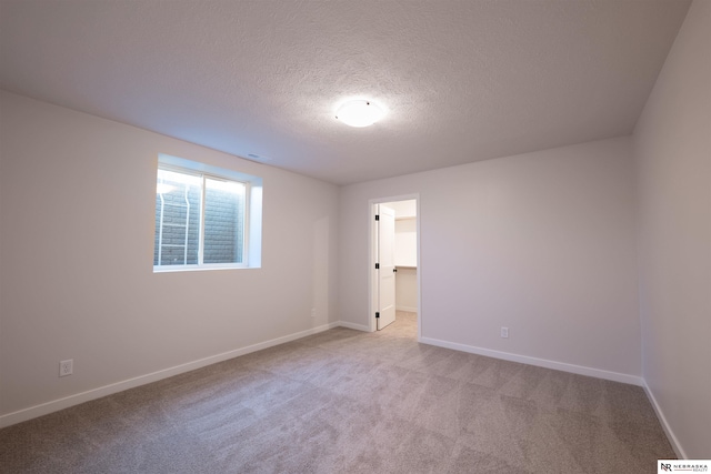 unfurnished room with light carpet and a textured ceiling