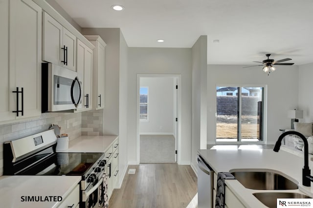 kitchen with stainless steel appliances, tasteful backsplash, light countertops, white cabinetry, and a sink