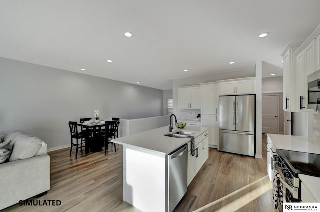 kitchen featuring stainless steel appliances, a sink, light countertops, and white cabinets