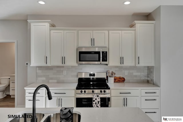 kitchen with tasteful backsplash, white cabinetry, stainless steel appliances, and a sink