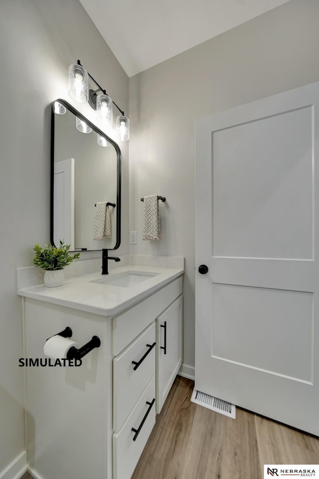 bathroom featuring visible vents, wood finished floors, vanity, and baseboards