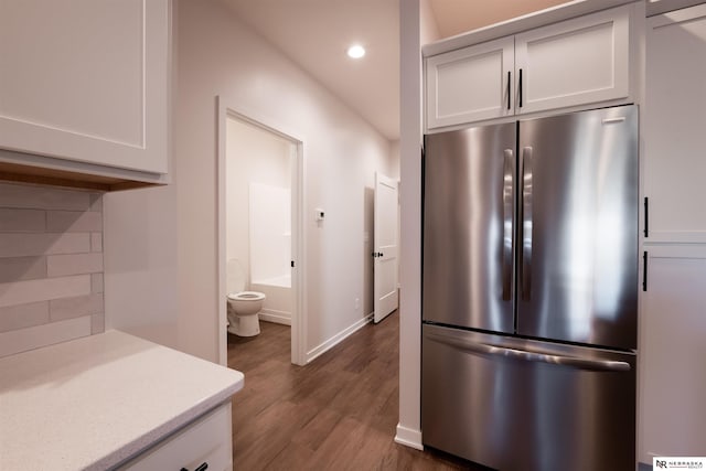 kitchen featuring white cabinetry, dark wood-type flooring, stainless steel fridge, and decorative backsplash