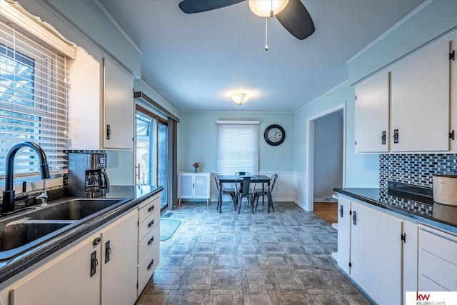 kitchen with tasteful backsplash, ornamental molding, sink, and white cabinets