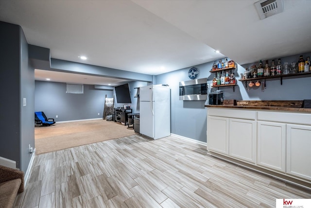 interior space featuring white refrigerator, butcher block counters, white cabinets, and light wood-type flooring