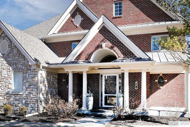 view of front of home with stone siding, brick siding, and roof with shingles