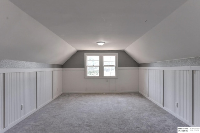 additional living space featuring lofted ceiling and light carpet