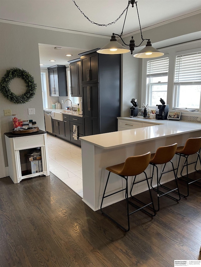 kitchen with crown molding, a kitchen bar, wood-type flooring, and hanging light fixtures