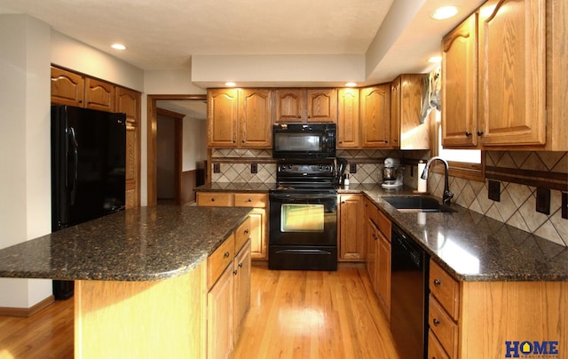 kitchen featuring light wood-type flooring, sink, a kitchen island, and black appliances