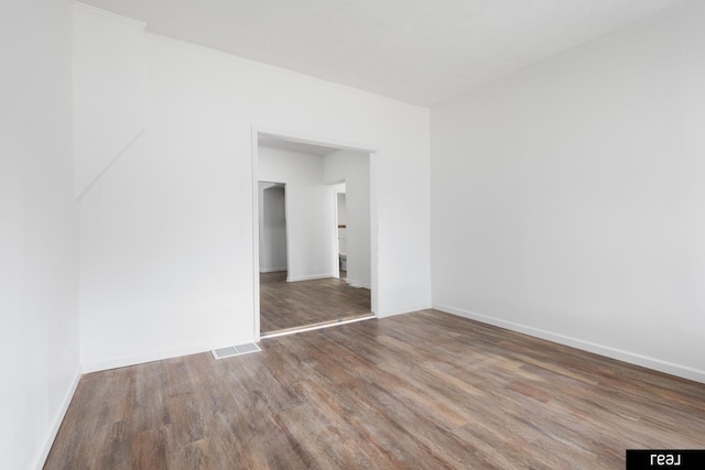 unfurnished room with visible vents, baseboards, and wood finished floors