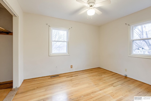 unfurnished bedroom featuring ceiling fan, a closet, multiple windows, and light hardwood / wood-style flooring