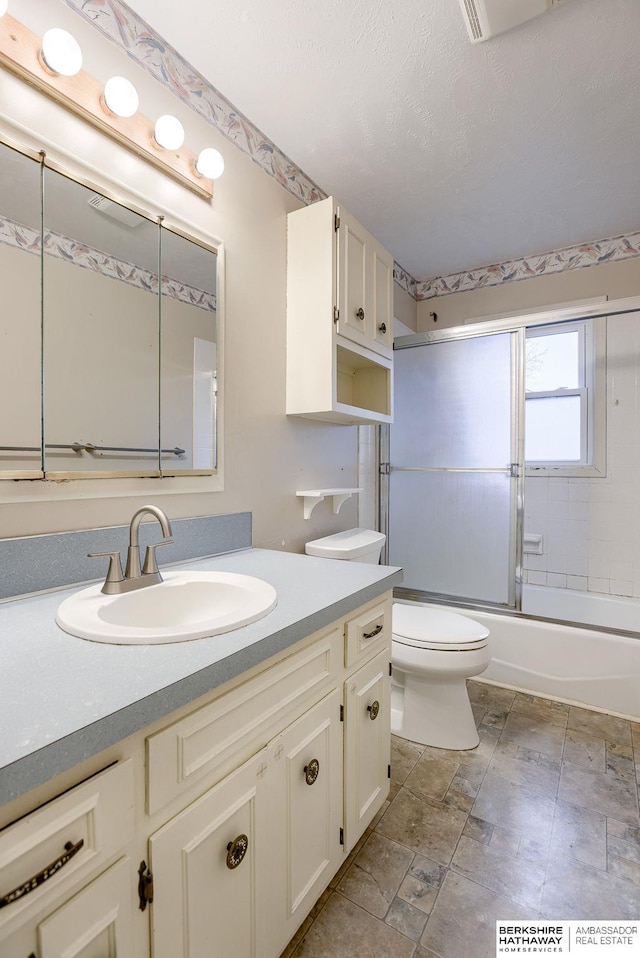 full bathroom featuring vanity, a textured ceiling, toilet, and combined bath / shower with glass door