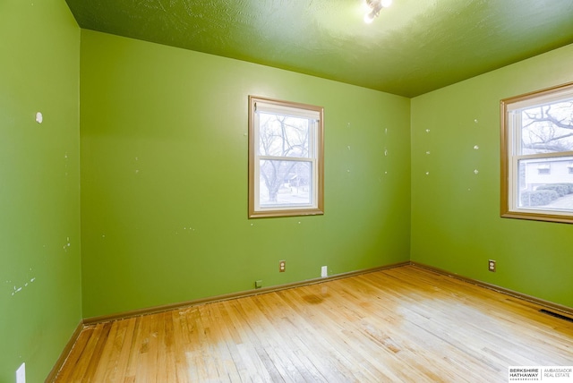 empty room featuring a textured ceiling and light wood-type flooring