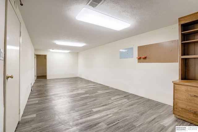 basement featuring wood-type flooring and a textured ceiling