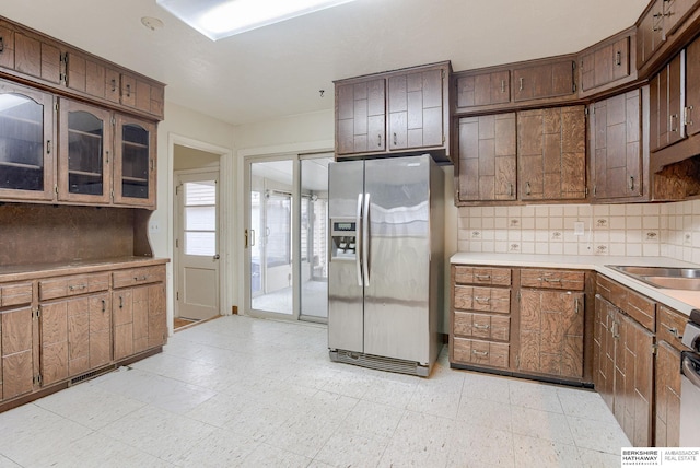 kitchen featuring stove, sink, stainless steel fridge, and decorative backsplash