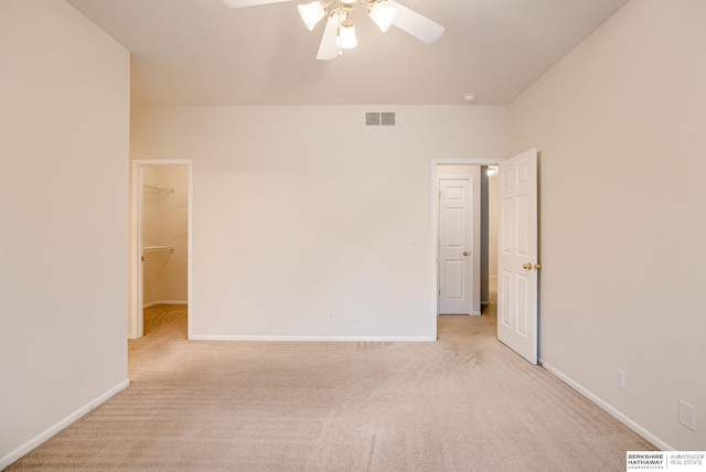 unfurnished bedroom with a spacious closet, light colored carpet, and ceiling fan