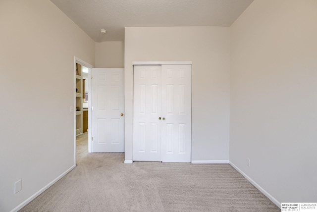 unfurnished bedroom featuring light carpet, a closet, and a textured ceiling