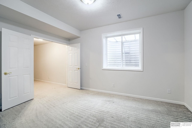 carpeted empty room featuring a textured ceiling