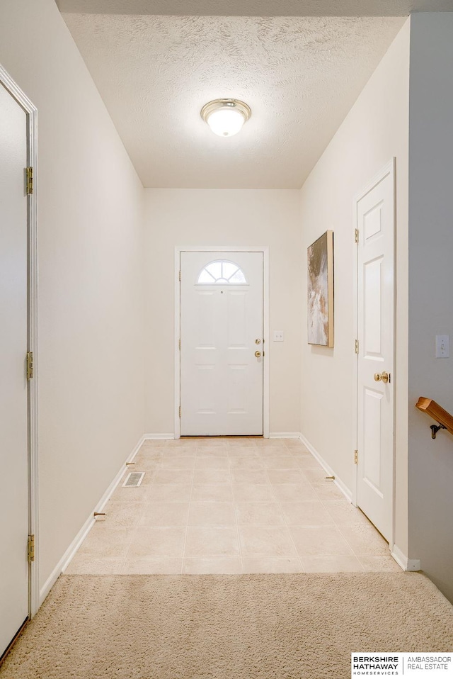 entryway with a textured ceiling and light tile patterned floors