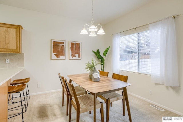 dining area with light colored carpet and a notable chandelier