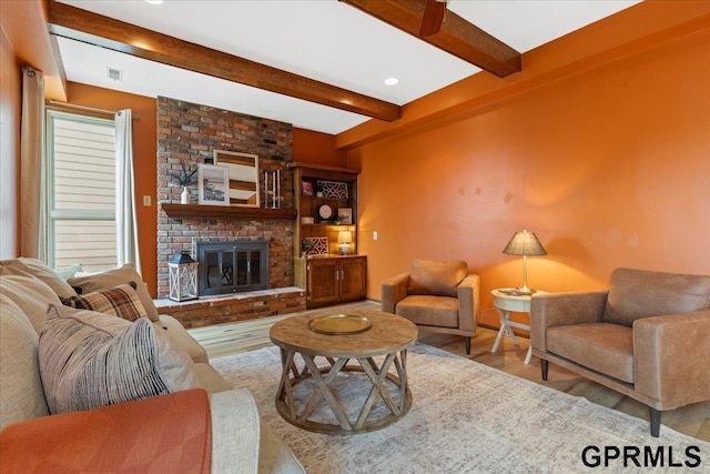 living room featuring wood-type flooring, a brick fireplace, and beam ceiling