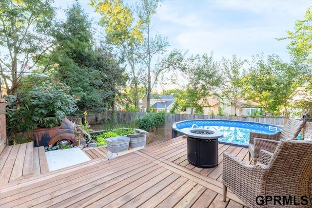 wooden terrace with a fenced in pool and an outdoor fire pit