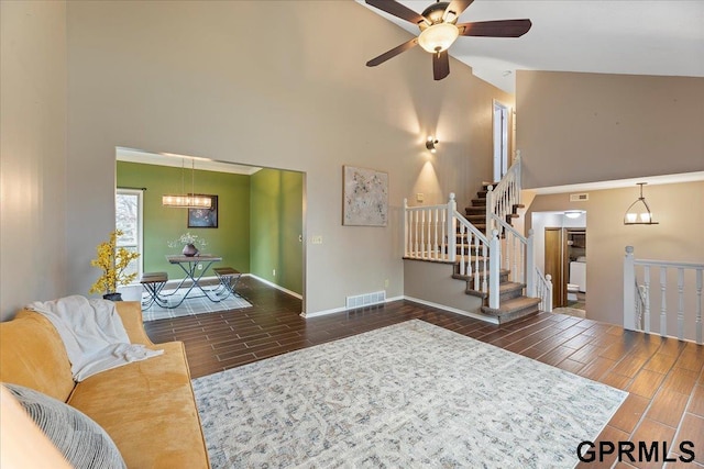 living room featuring ceiling fan with notable chandelier and high vaulted ceiling