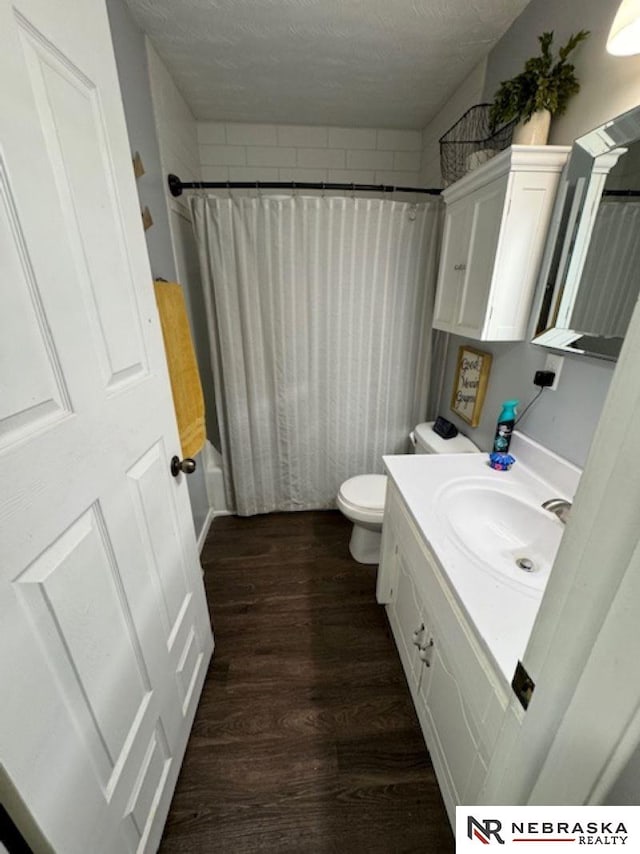 full bathroom with hardwood / wood-style floors, vanity, a textured ceiling, toilet, and shower / bath combo with shower curtain