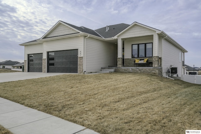 view of front of house featuring a garage, cooling unit, covered porch, and a front lawn