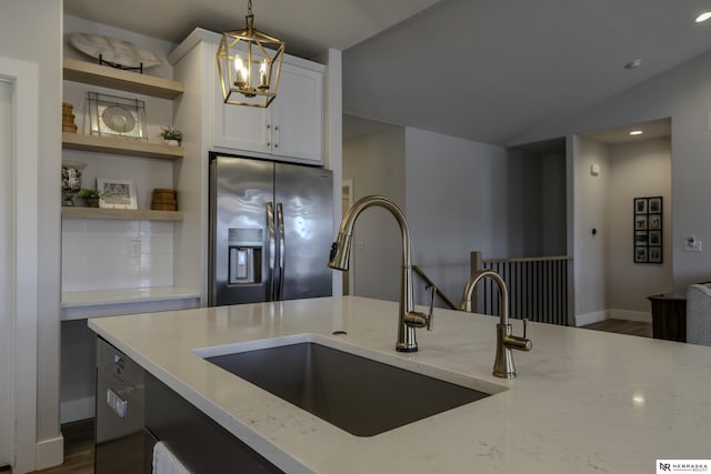 kitchen with pendant lighting, sink, light stone countertops, and stainless steel fridge with ice dispenser