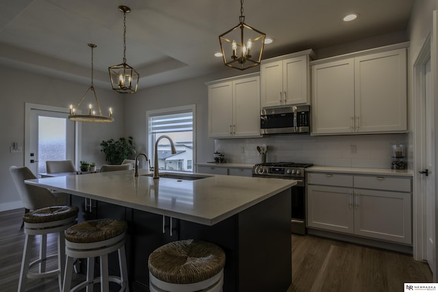 kitchen featuring stainless steel appliances, an island with sink, and hanging light fixtures