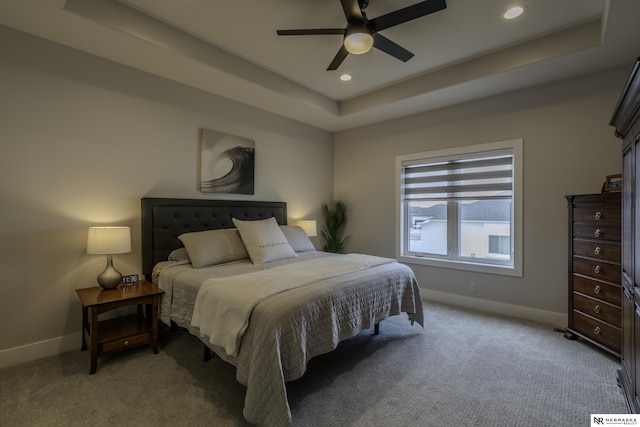 carpeted bedroom featuring a raised ceiling and ceiling fan