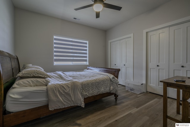 bedroom featuring ceiling fan, dark hardwood / wood-style floors, and two closets