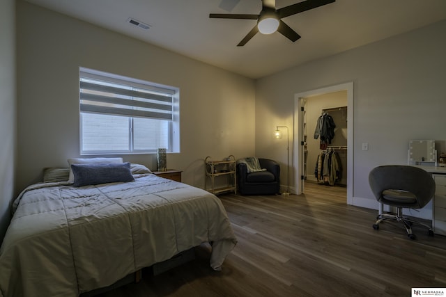 bedroom with wood-type flooring, a spacious closet, ceiling fan, and a closet